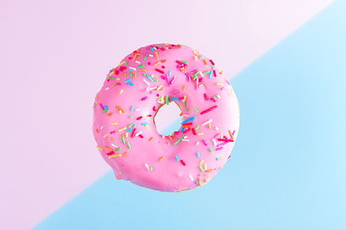 one falling sweet doughnut on blue and pink abstract background with copy space