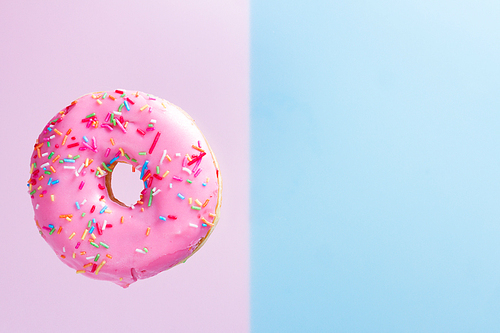 one falling sweet doughnut on blue and pink background with copy space