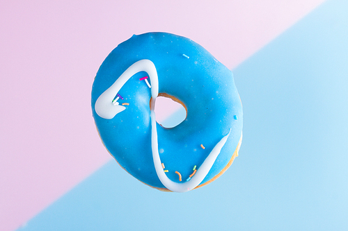 one falling sweet doughnut on blue and pink background