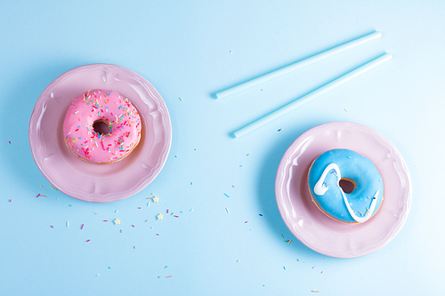 Two sweet doughnuts on blue background with copy space