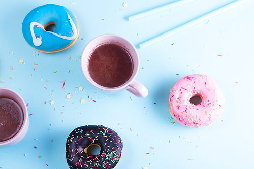 Two sweet doughnuts with cacao drink on blue background with copy space, top view scene