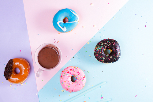 Two sweet doughnuts with cacao on blue, violet and pink background with copy space, top view scene