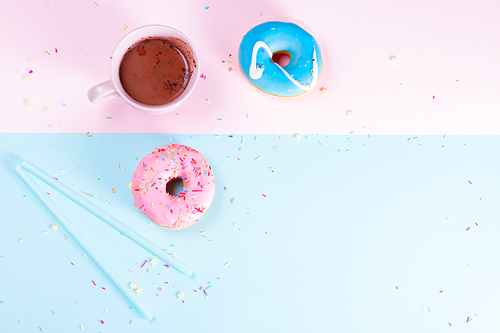 Two sweet doughnuts with cacao on blue and pink background with copy space