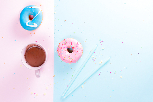 Two sweet doughnuts with cacao drink on blue and pink background with copy space