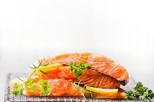 Raw salmon with lemon for tasty cooking on light background, side view
