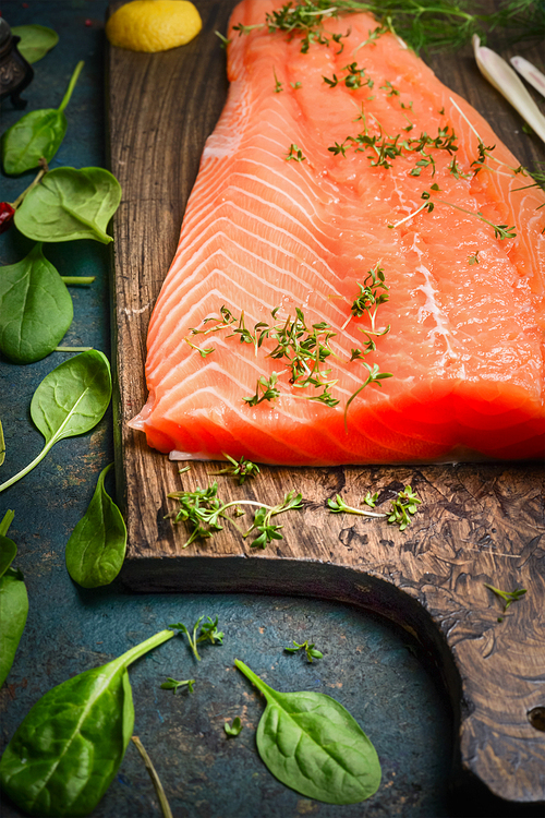 Salmon fillets on cutting board and fresh ingredients for cooking, close up
