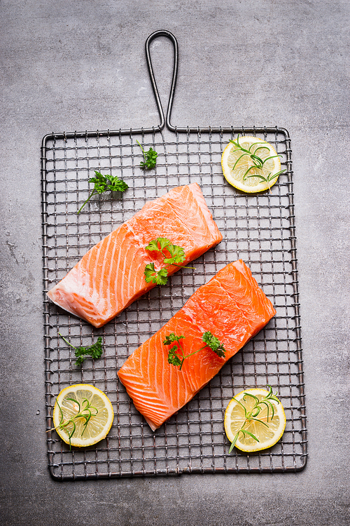 Raw Salmon fillet portion with lemon and herbs , top view