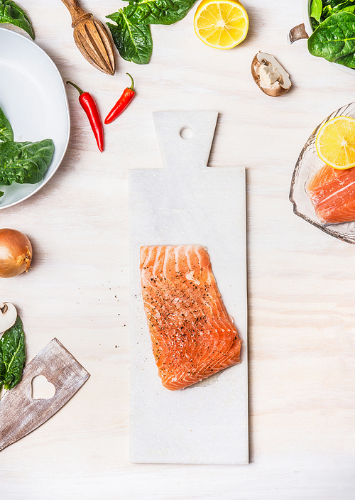 Raw Salmon fillets on white cutting board with healthy ingredients on kitchen table background, top view.  Diet  nutrition and healthy food concept