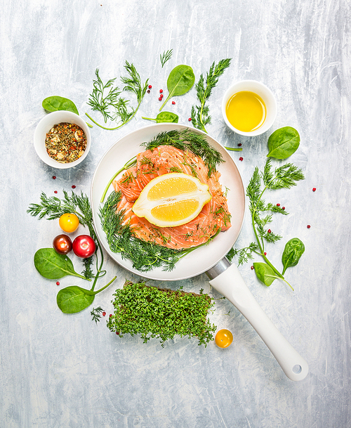 raw salmon in white pan with lemon and fresh herbs, top view