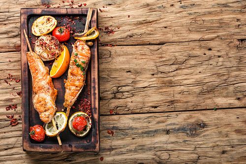 Grilled fish with lemon on rustic dark wooden background