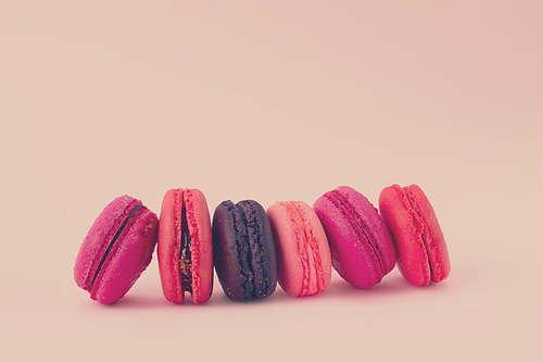 Pink macaroons cookies row on on pink background, retro toned