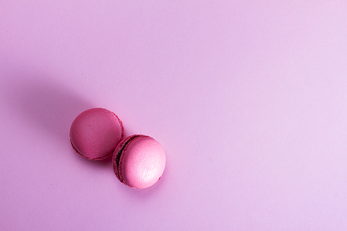 Two Macaroons cookies on pink background with copy space