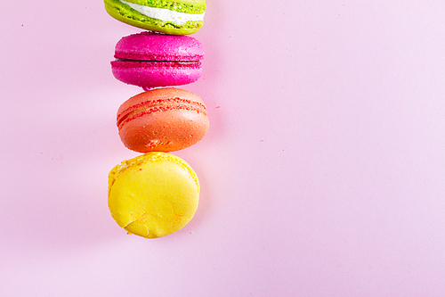 Macaroons cookies row on pink background with copy space