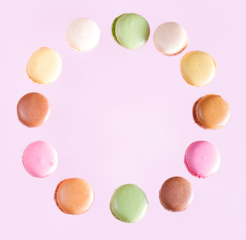 Multicolored macaroons falling frame on pink background