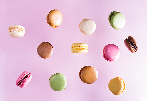 Assorted macaroons falling cookies on pink background