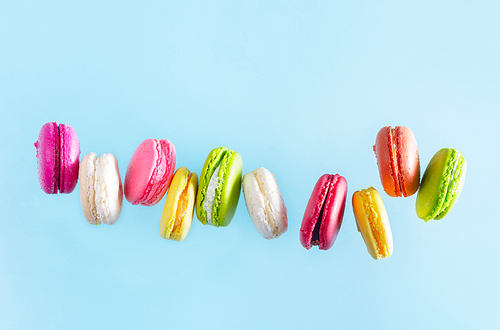 Assorted macaroons falling cookies on blue background