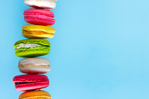 Assorted macaroons cookies row with copy space on blue background