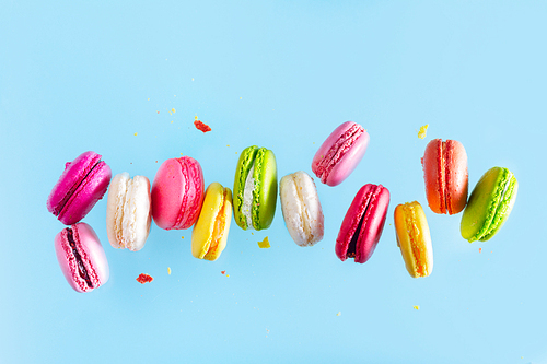 Assorted colorful macaroons falling cookies on blue background