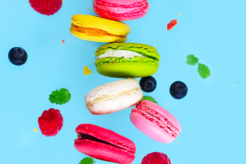 Assorted macaroons falling cookies with berries close up on blue background