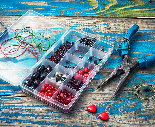 plastic box with beads and accessories for needlework on outdated wooden background