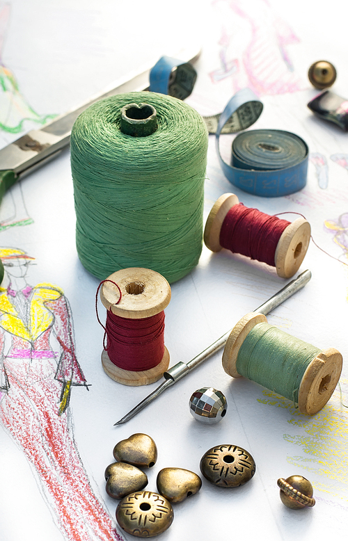 Spools of thread for sewing on the background of the sketch clothing
