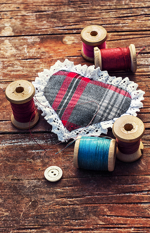 button and spools of thread for needlework on bright background