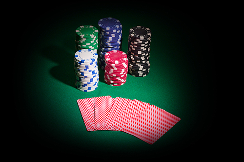 Chips and playing cards on green table