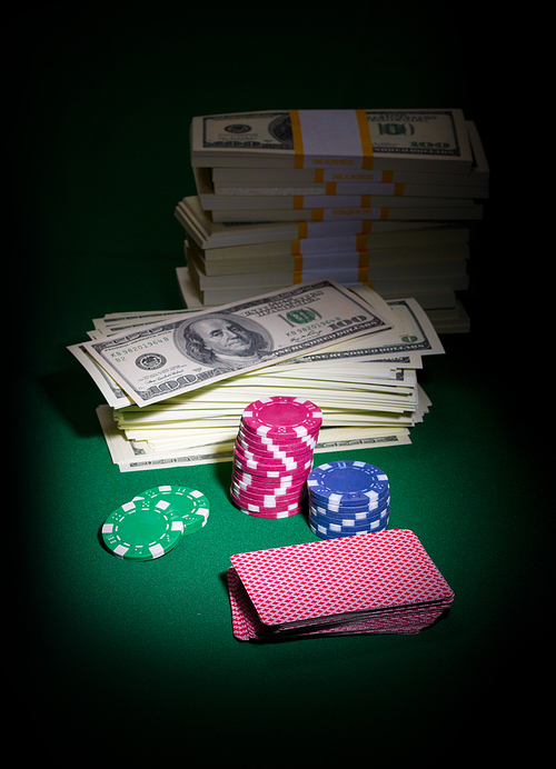 Playing cards chips and dollars on green table