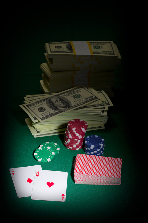 Stack of dollars chips and playing cards on green table