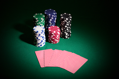 Gambling chips and playing cards on green table