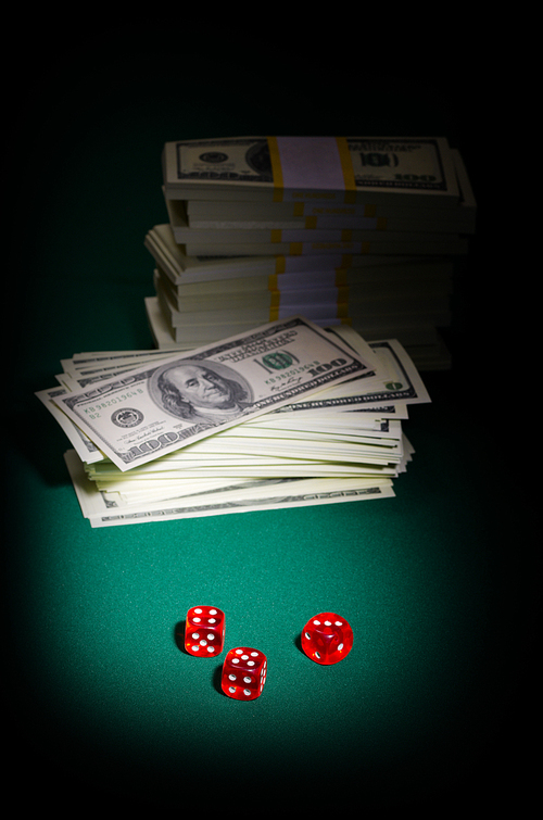 Stack of dollars and dices on green table