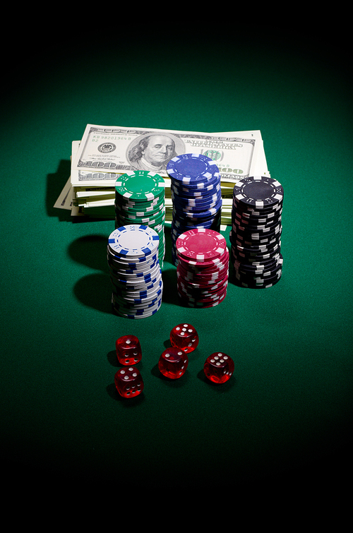 Gambling chips dollars and dices on green table