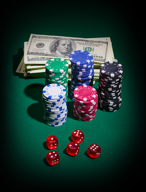 Stack of dollars dices and chips on green table