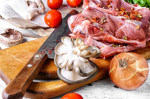 raw meat selection and mushroom on wooden cutting board with knife