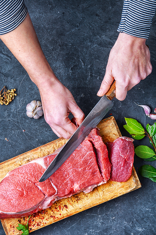 Man slicing beef stead on wooden cutting board