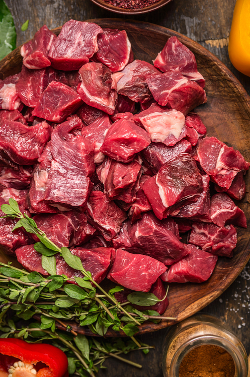 Raw  uncooked meat sliced in cubes on wooden rustic background, top view, close up