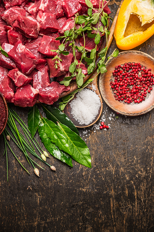 Chopped raw meat with vegetables, herb and spices for goulash on  rustic wooden background, top view, place for text