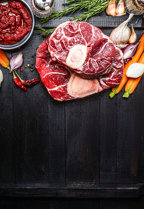 Veal shank slices meat and ingredients for Osso Buco cooking on dark wooden background,  top view, vertical border