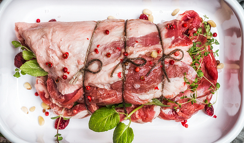 Raw meat roast preparation with fresh cooking herbs,spices, Pine nuts and cranberries , top view, close up