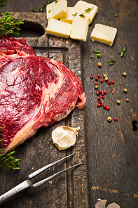 Raw beef meat with ingredients for cooking on rustic wooden background