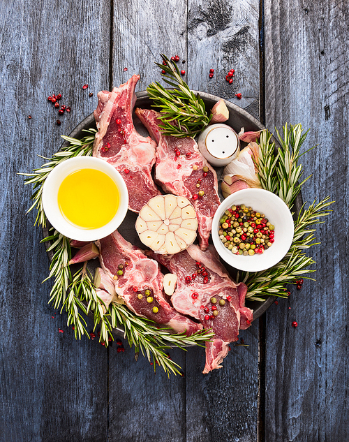 lamb raw loin chops meat with oil, pepper and seasoning on blue wooden background, top view
