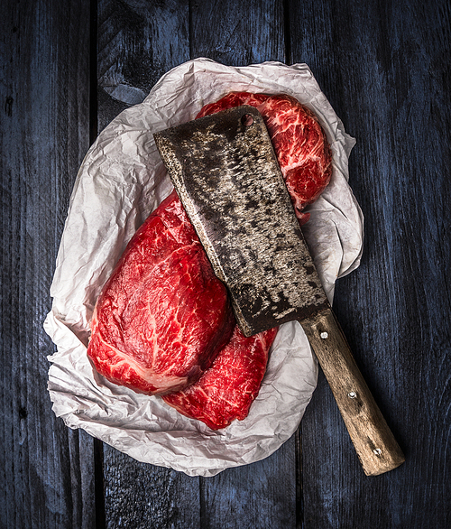 raw beef  with old meat cleaver on dark blue wooden background, top view