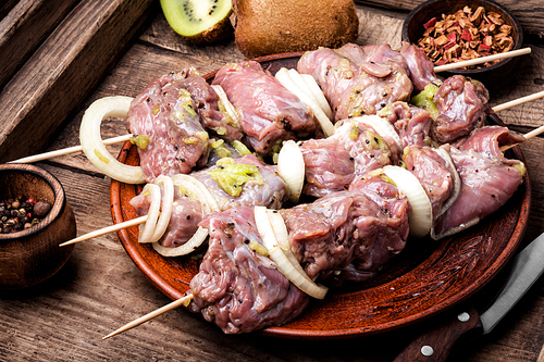 Fresh raw meat skewers kebabs on plate.Meat prepared for marinating on cutting board