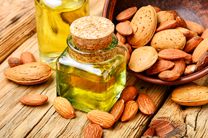 Almond oil in glass bottle and almonds on retro table.Almond massage oil