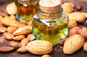 Almond oil in glass bottle and almonds