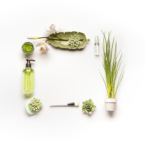 Modern facial skin care setting . Herbal cosmetic concept.  Frame of green cosmetic products, accessories, plants and orchid flowers on white desktop background, top view, copy space, flat lay