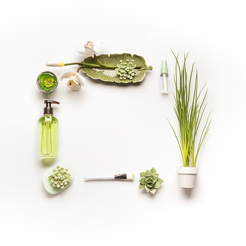 Modern facial skin care setting . Herbal cosmetic concept.  Frame of green cosmetic products, accessories, plants and orchid flowers on white desktop background, top view, copy space, flat lay