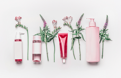 Pink herbal natural facial cosmetic products set with herbs and flowers on white background, top view. Branding mock up