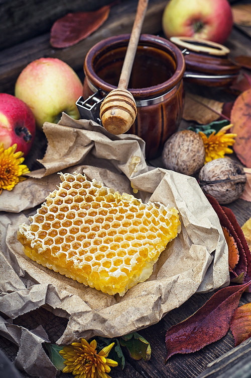 Honeycomb wrapped in grey paper on the background of the jars