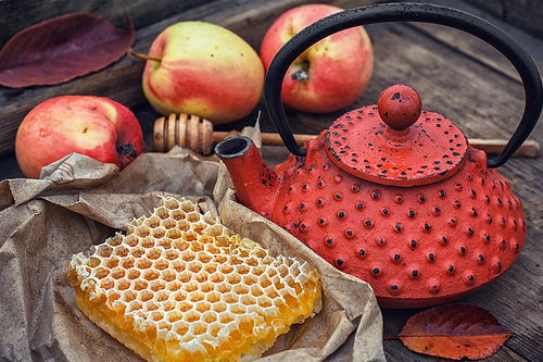 Honeycomb wrapped in grey paper on the background of the red kettle